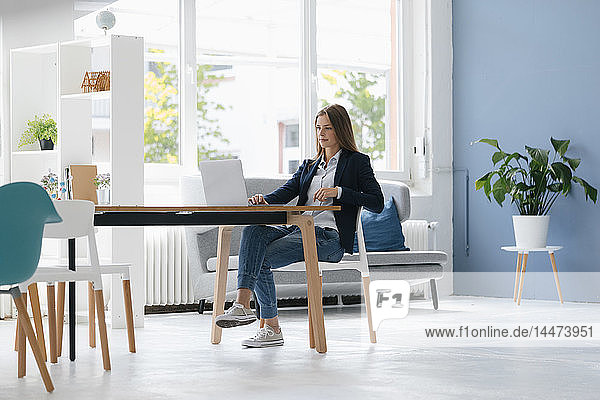 Junge Geschäftsfrau sitzt im Büro und benutzt Laptop