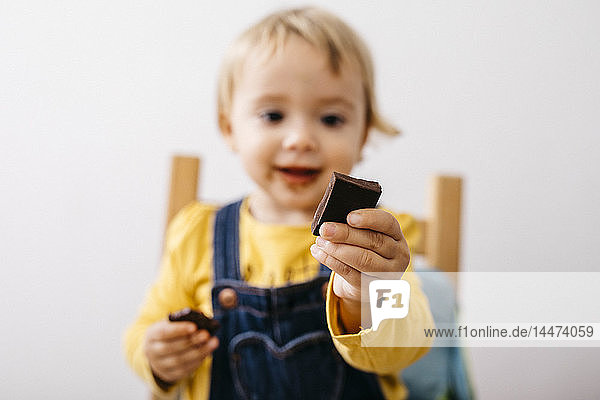 Hand eines lächelnden Kleinkindes mit einem Stück Schokolade in der Hand  Nahaufnahme