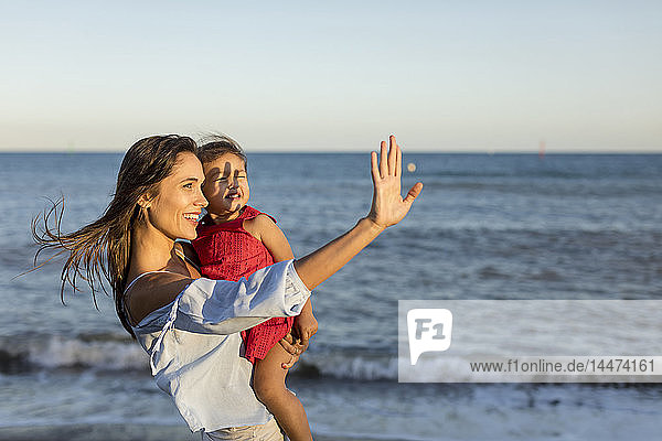 Mother and daughter standing on the beach at sunset