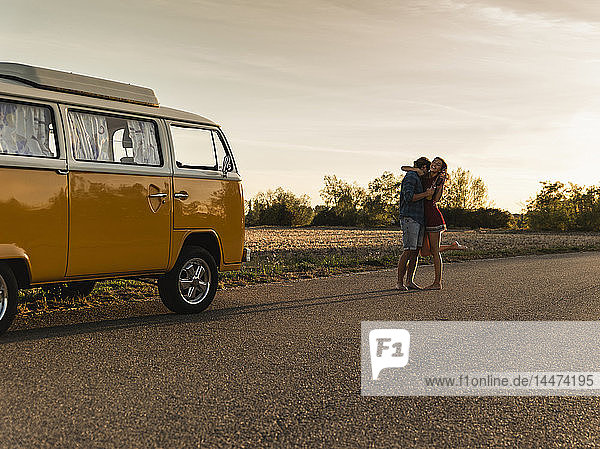 Glückliches Paar macht eine Autoreise mit einem Wohnmobil  lacht und umarmt sich unterwegs