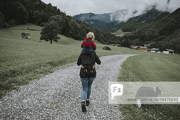 Österreich  Vorarlberg  Mellau  Mutter trägt Kleinkind auf den Schultern bei einem Ausflug in die Berge
