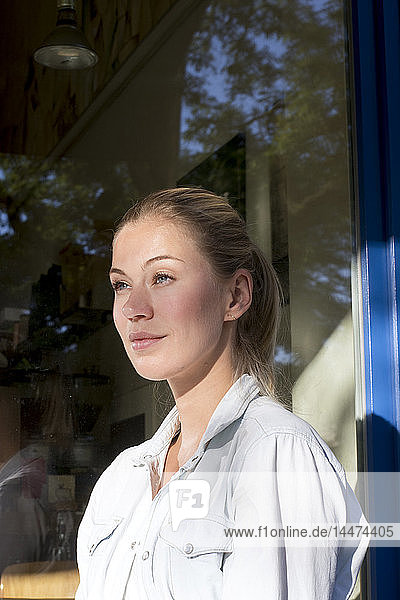 Portrait of smiling woman in front of window looking at distance