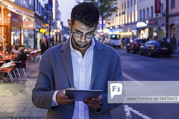 Deutschland  München  junger Geschäftsmann mit digitalem Tablet in der Stadt in der Abenddämmerung