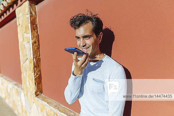 Lächelnder Mann benutzt Handy an einem sonnigen Tag