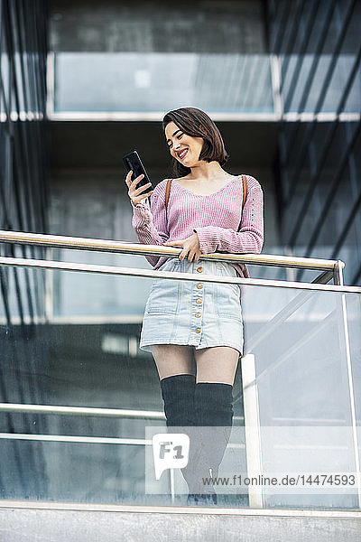 Lächelnde junge Frau schaut auf Handy