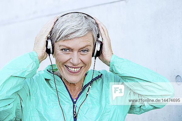 Porträt einer lächelnden  sportlichen  reifen Frau mit Kopfhörern