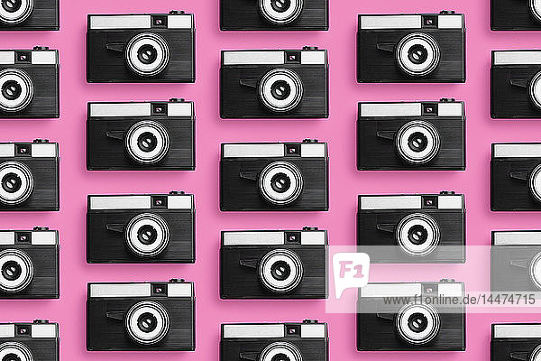 Plastik-Fotokameras in einer Reihe über rosa Hintergrund