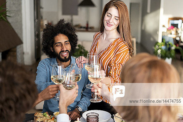 Friends drinking wine at a dinner party  clinking glasses