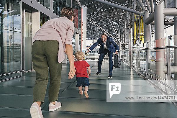 Glückliches Kind rennt auf dem Flughafen in die Arme eines reisenden Geschäftsmannes