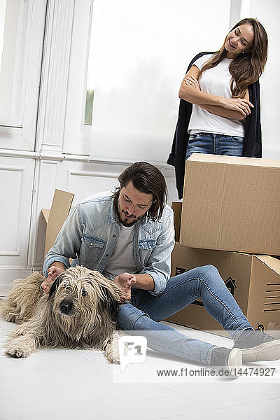 Couple with dog and cardboard boxes in new home
