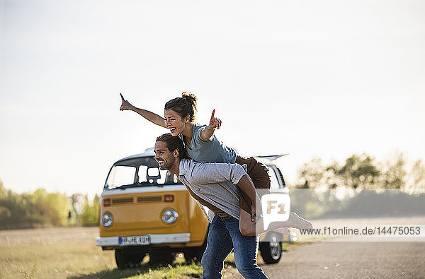 Happy couple doing a road trip with a camper  pretending to fly on the road