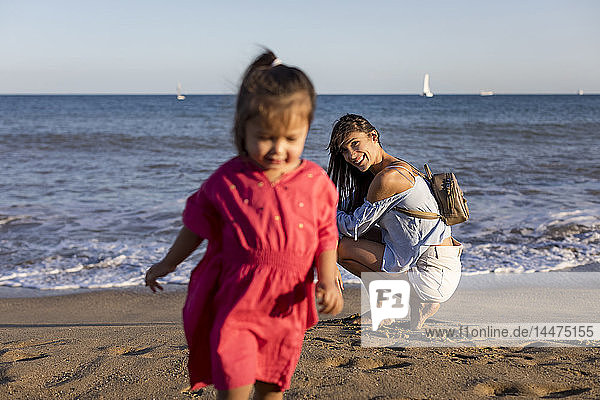 Mutter beobachtet rennende Tochter am Strand