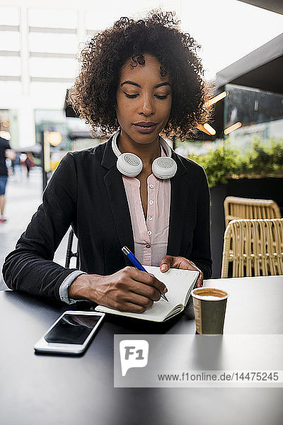 Porträt einer Geschäftsfrau  die sich im Straßencafé Notizen macht