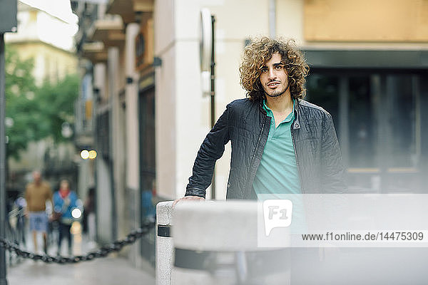 Portrait of young man with beard and curly hair outdoors