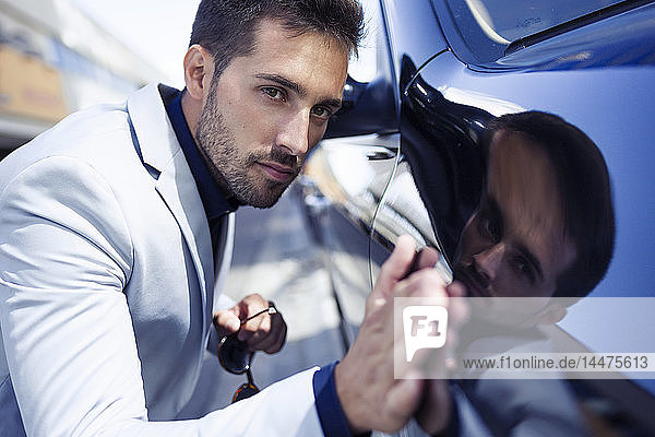 Young businessman stroking his polished car