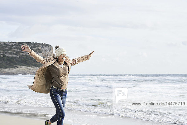 Spanien  Menorca  glückliche ältere Frau  die im Winter am Strand läuft