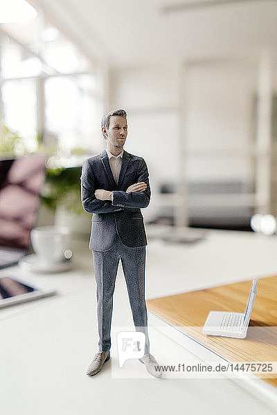 Geschäftsmann-Figur auf einem Schreibtisch stehend mit mobilen Geräten