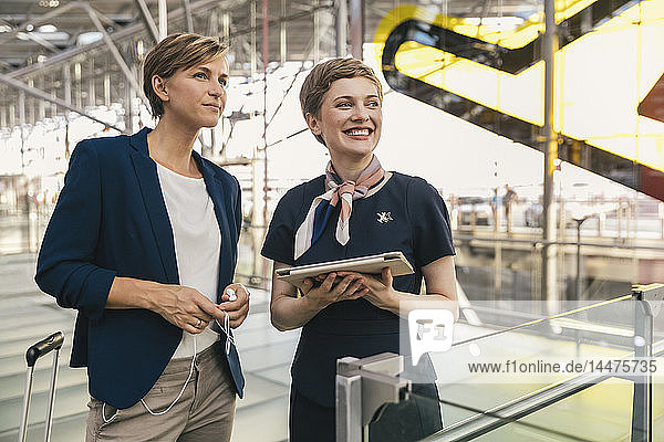 Lächelnder Fluglinienangestellter mit Tablette und Geschäftsfrau am Flughafen