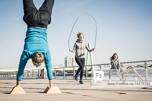 Friends training at the riverside  skipping rope and doing handstand
