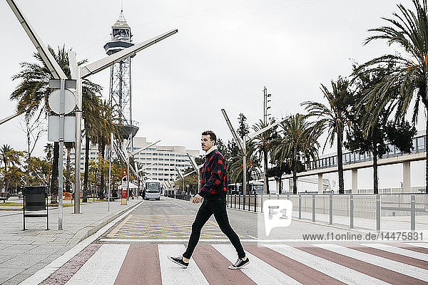 Junger Mann in legerer Kleidung geht auf einem Fußgängerüberweg in Barcelona