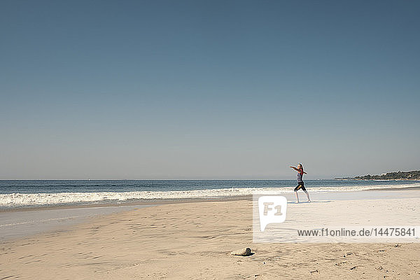 Junge Frau übt Yoga am Strand aus