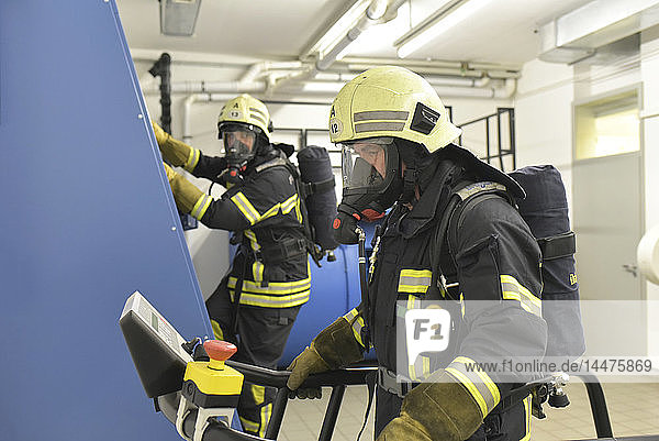 Zwei Feuerwehrleute mit Atemschutzgerät und Luftbehälter üben im Übungsraum