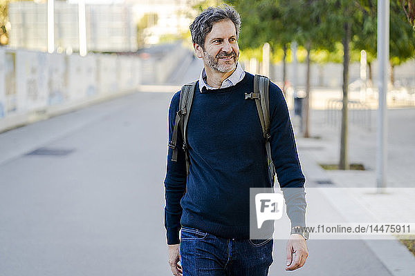 Smiling mature man with a backpack in the city on the go