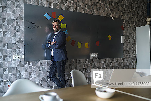 Businessman standing in front of magnet wall with a colorful headdress  made from sticky notes