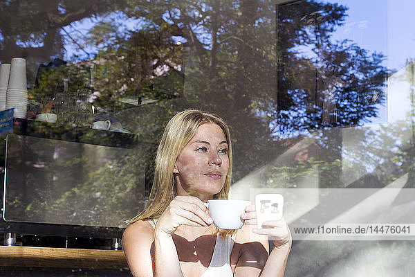 Portrait of woman in a cafe with cup of coffee looking out of window