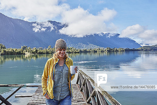 Chile  Chaiten  Lago Rosselot  woman walking on jetty holding mug