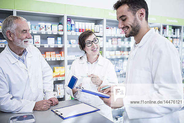 Smiling pharmacists with clipboard at counter in pharmacy