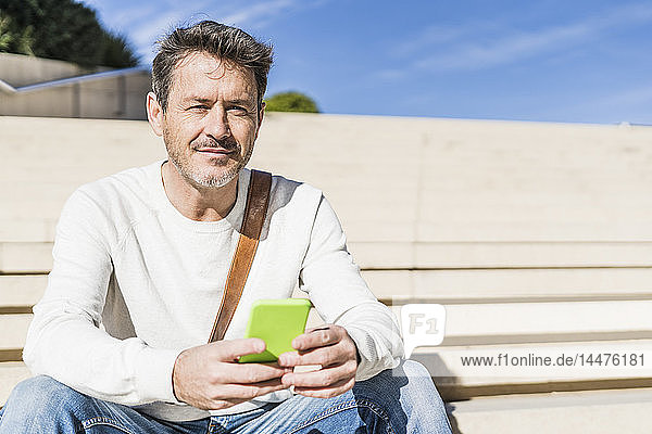 Casual businessman sitting on stairs  holding smarthone