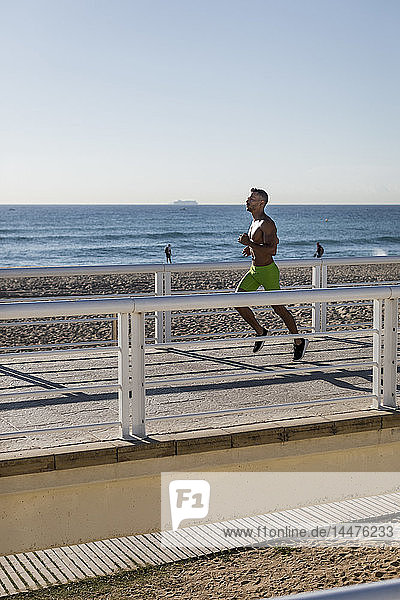 Barbusiger Mann rennt auf Uferpromenade