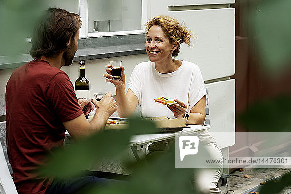 Glückliches Paar sitzt im Garten  isst Pizza  trinkt Wein
