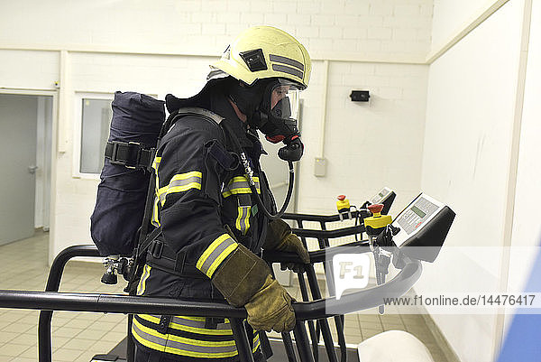 Feuerwehrmann mit Atemschutzgerät und Luftkessel beim Training auf dem Laufband