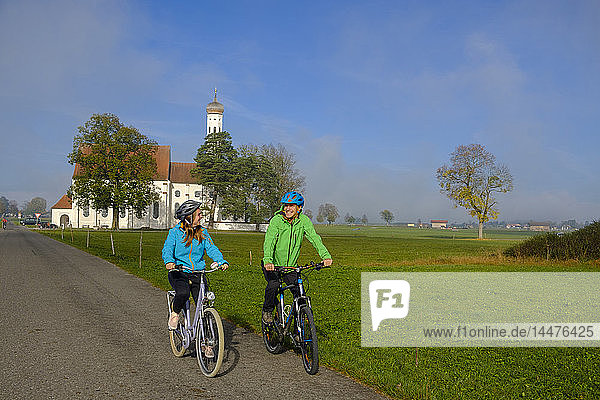 Deutschland  Wallfahrtskirche St. Coloman und ein Radlerpaar auf Tour