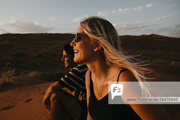 Namibia  Namib desert  Namib-Naukluft National Park  Sossusvlei  happy couple sitting on Elim Dune at sunset