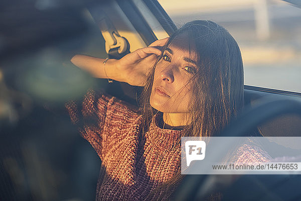 Porträt einer ernsten Frau  die bei Sonnenuntergang im Auto sitzt