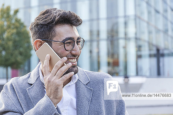 Portrait of laughing young businessman on the phone