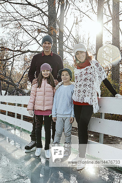 Familie lehnt sich auf dem Geländer der Eisbahn ab