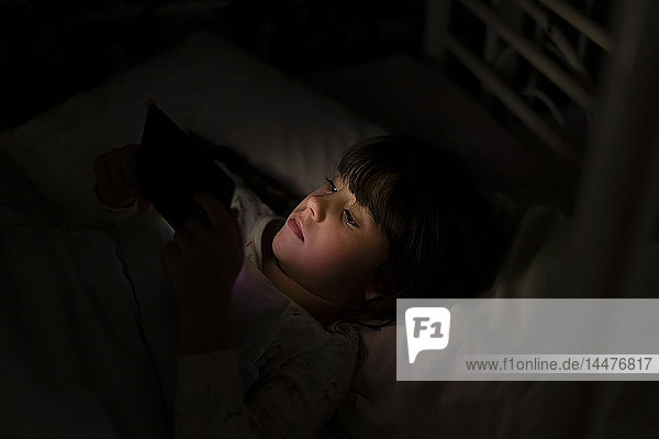 Girl lying in bed using smartphone at night