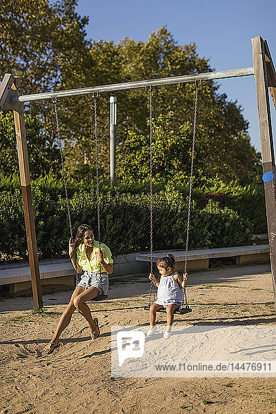 Glückliche Mutter und Tochter auf einer Schaukel auf einem Spielplatz