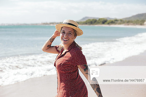 Spanien  Mallorca  Porträt einer glücklichen jungen Frau mit Tätowierungen am Strand