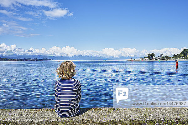 Chile  Puerto Montt  Junge sitzt auf der Kaimauer des Hafens