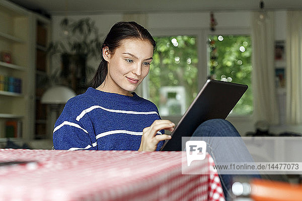 Young woman sitting at home  using digital tablet