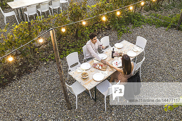 Italien  Toskana  Siena  junges Paar bei einem romantischen Abendessen in einem Weinberg