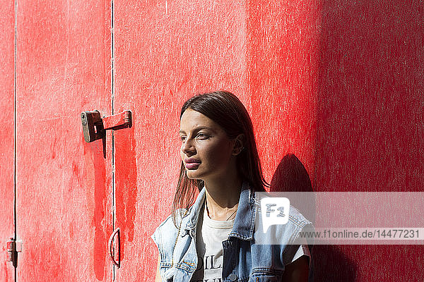 Porträt einer tagträumenden jungen Frau vor rotem Hintergrund