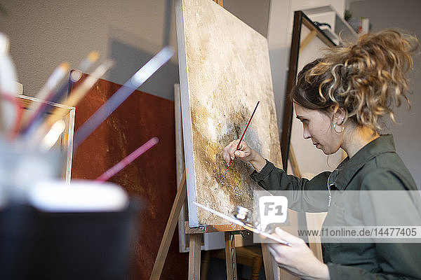 Junge Frau malt in ihrem Atelier