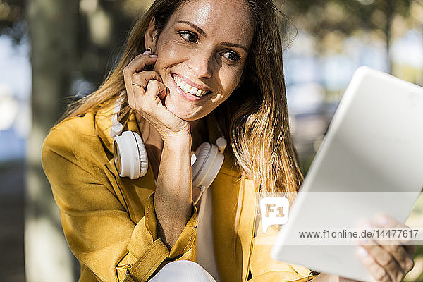 Lächelnde Frau in einem Park mit Tablette