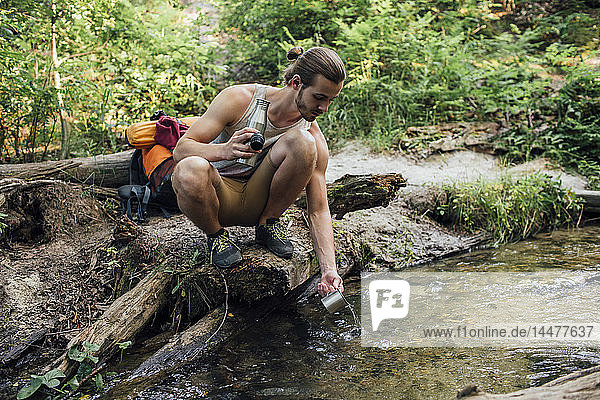 Junger Wanderer schöpft Süßwasser in einem Wald